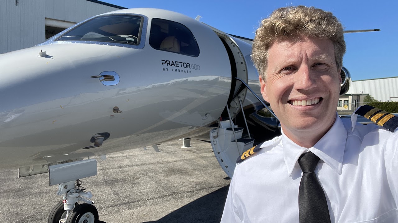 Aced Aviation pilot in uniform beside an Embraer Praetor 600